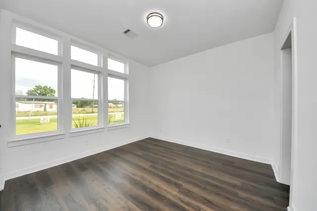 an empty room with wooden floor and windows