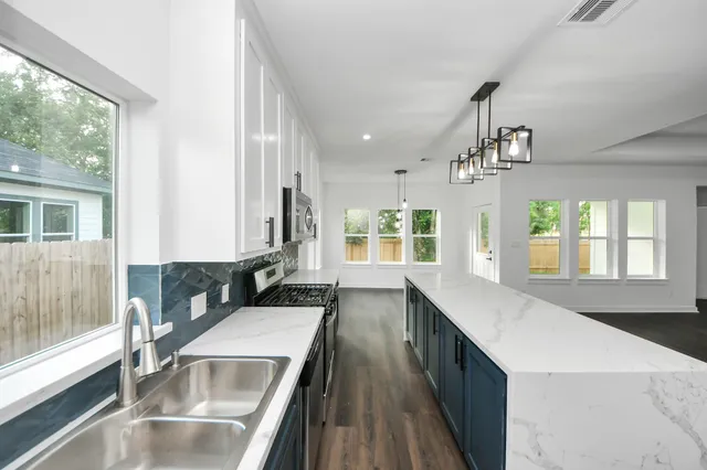 a large kitchen with kitchen island a large window a sink and stainless steel appliances