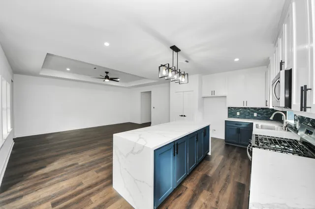 a large kitchen with stainless steel appliances kitchen island a large counter top and wooden floors