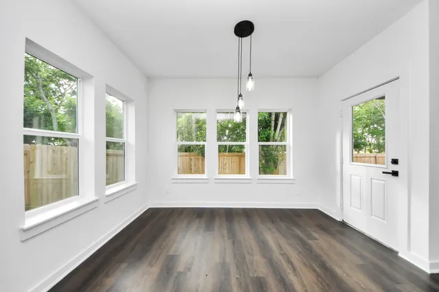 a view of an empty room with a window and wooden floor