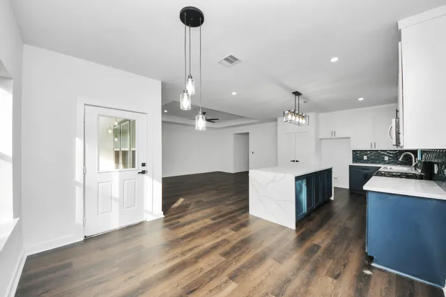 a large kitchen with a center island wooden floor and stainless steel appliances