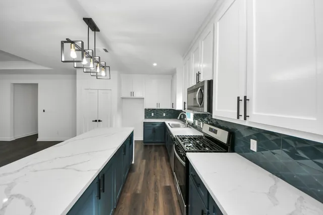 a large white kitchen with a large counter top space appliances and cabinets