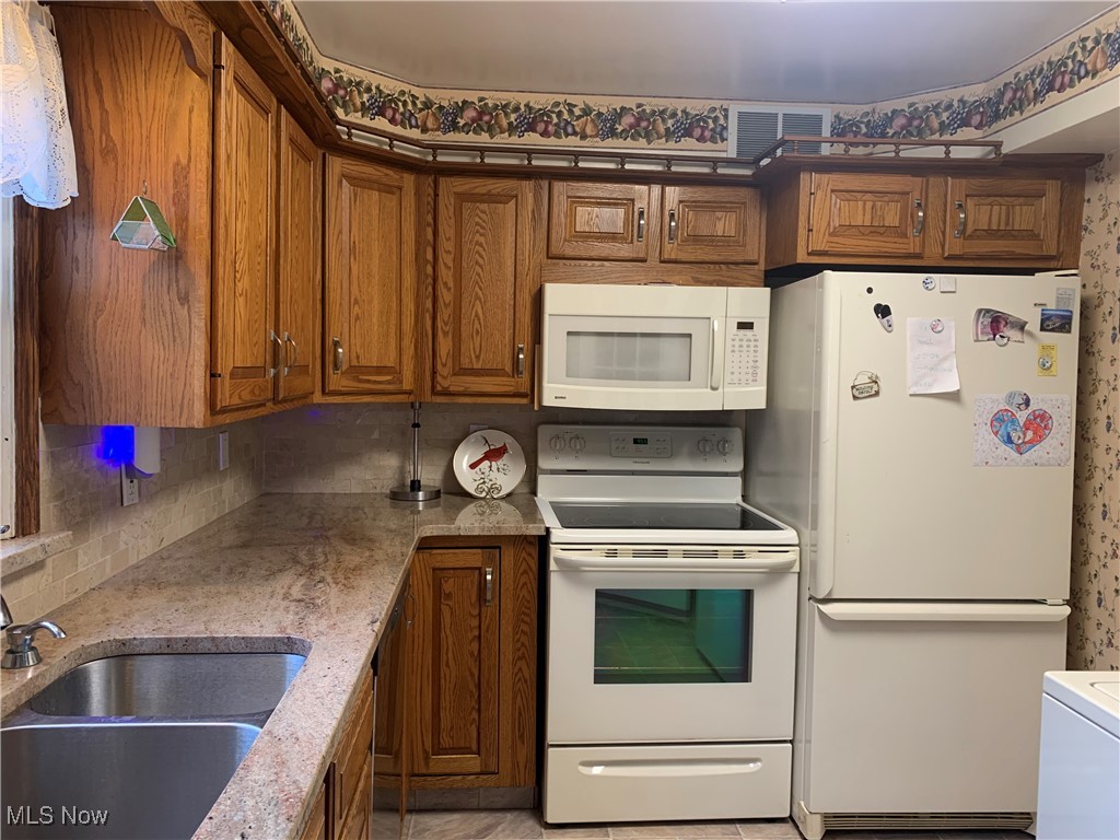 16879 Ridgeview Drive East Liverpool, OH 43920 - Photo 11 of 22 Kitchen with white appliances, light stone counters, tasteful backsplash, and sink