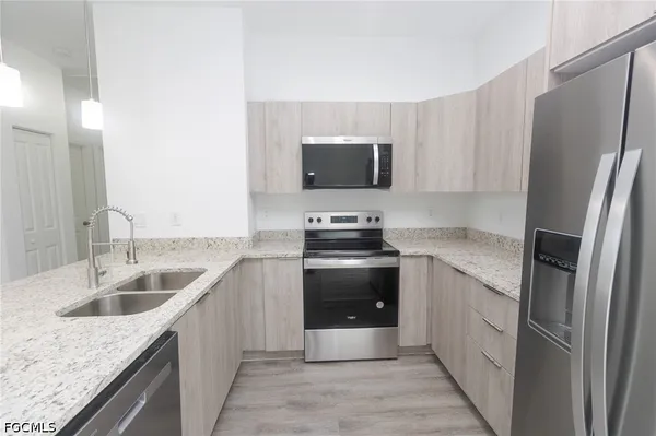 a kitchen with stainless steel appliances granite countertop a sink stove and refrigerator