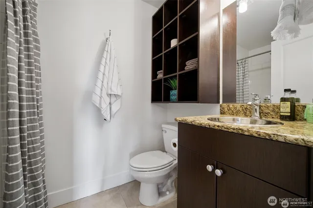 a bathroom with a granite countertop sink a toilet and a mirror
