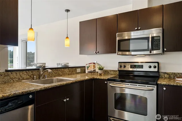 a kitchen with granite countertop a sink a stove and microwave