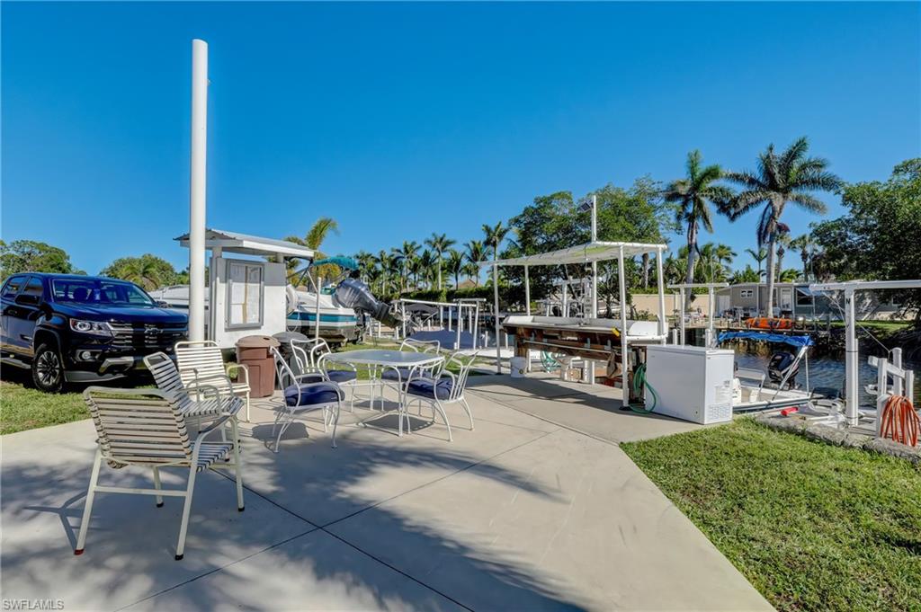 143 Rose Lane Naples, FL 34114 - Photo 8 of 13 a view of a patio with table and chairs potted plants and palm tree