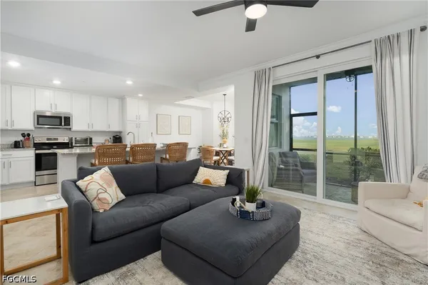 a living room with furniture and a large window with kitchen view