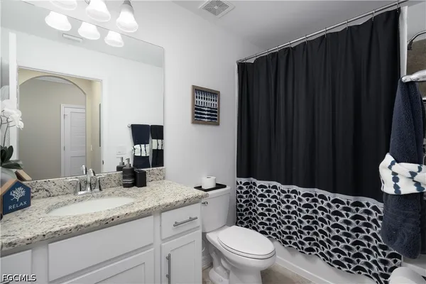 a bathroom with a granite countertop sink toilet and a mirror