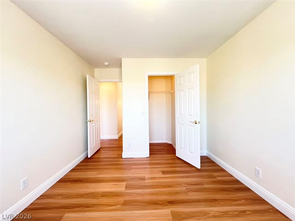 9891 Ridge Hill Avenue Las Vegas, NV 89147 - Photo 21 of 29 Golden-toned laminate floors complement the bright walls in this versatile bedroom space.