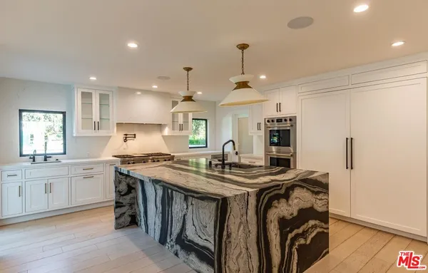 a kitchen with kitchen island a stove a sink a refrigerator and wooden cabinets