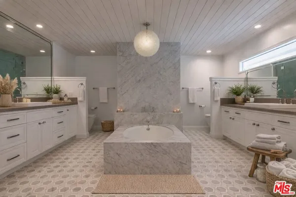 a spacious bathroom with a granite countertop sink a mirror and a bathtub