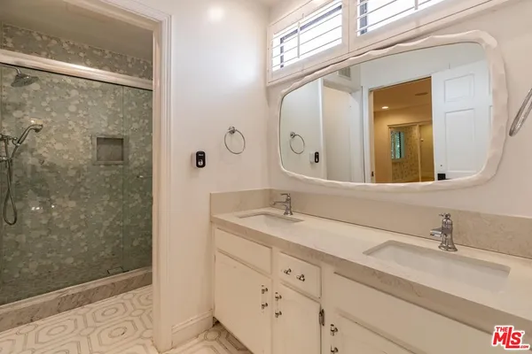 a bathroom with a granite countertop sink a mirror and shower
