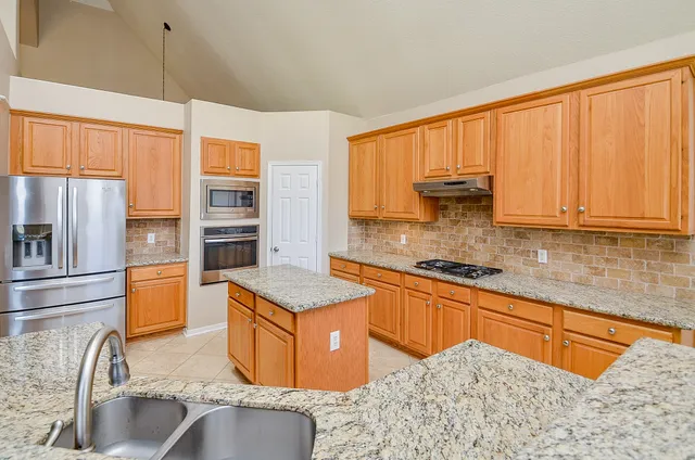 a kitchen with stainless steel appliances granite countertop a sink stove and refrigerator