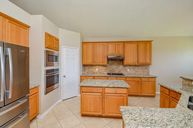 a kitchen with stainless steel appliances granite countertop a refrigerator stove top oven and sink