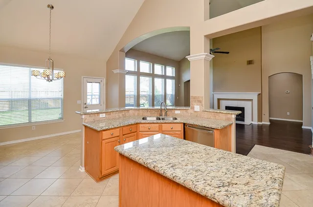 a large kitchen with kitchen island a sink granite counter tops and a fireplace