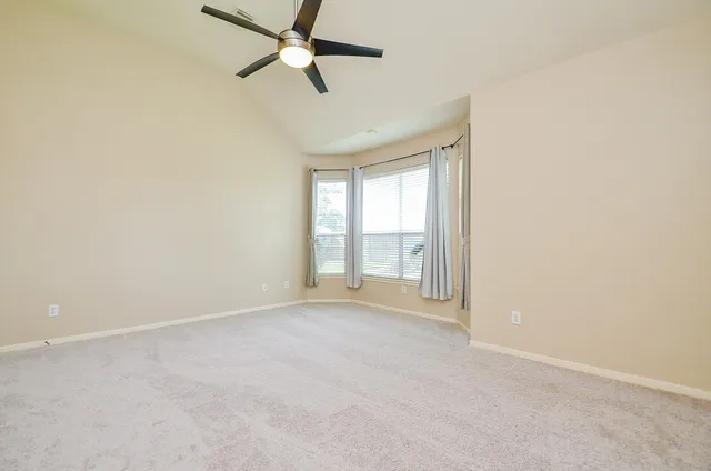 an empty room with a ceiling fan and window