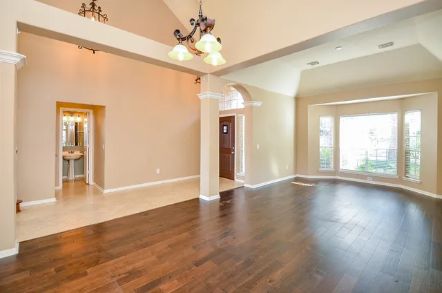 a view of an empty room with window and wooden floor