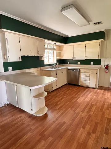 a kitchen with a white cabinets and wooden floor