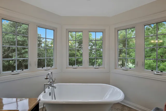 a white bath tub sitting in a bathroom next to a window