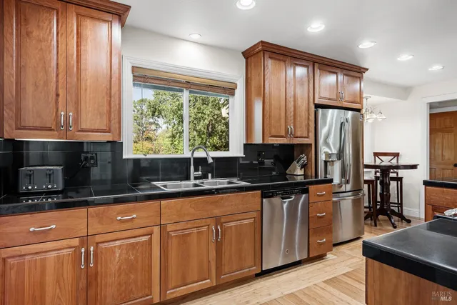 a kitchen with stainless steel appliances granite countertop a stove a sink dishwasher a refrigerator and a microwave oven with wooden floor