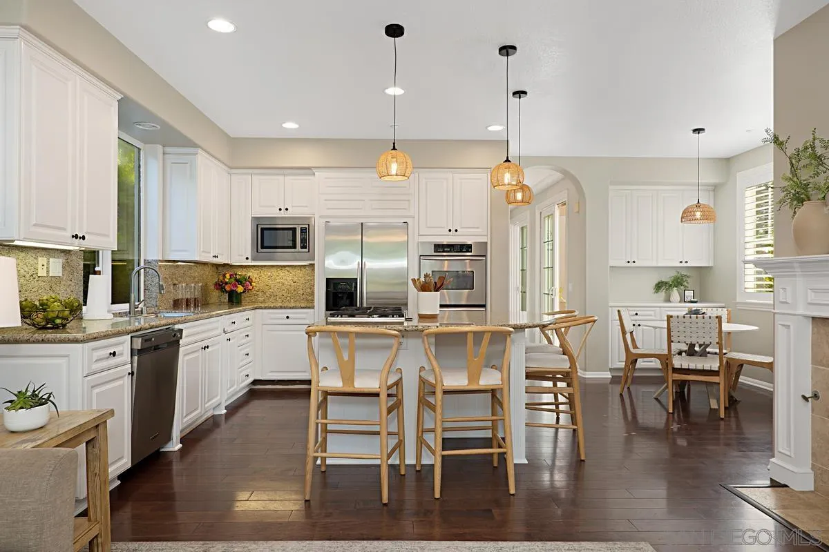 660 Cypress Hills Drive Encinitas, CA 92024 - Photo 10 of 38 a kitchen with stainless steel appliances kitchen island granite countertop a table chairs sink and cabinets