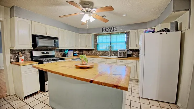 a kitchen with stainless steel appliances granite countertop a sink a stove a refrigerator a washer dryer and a refrigerator