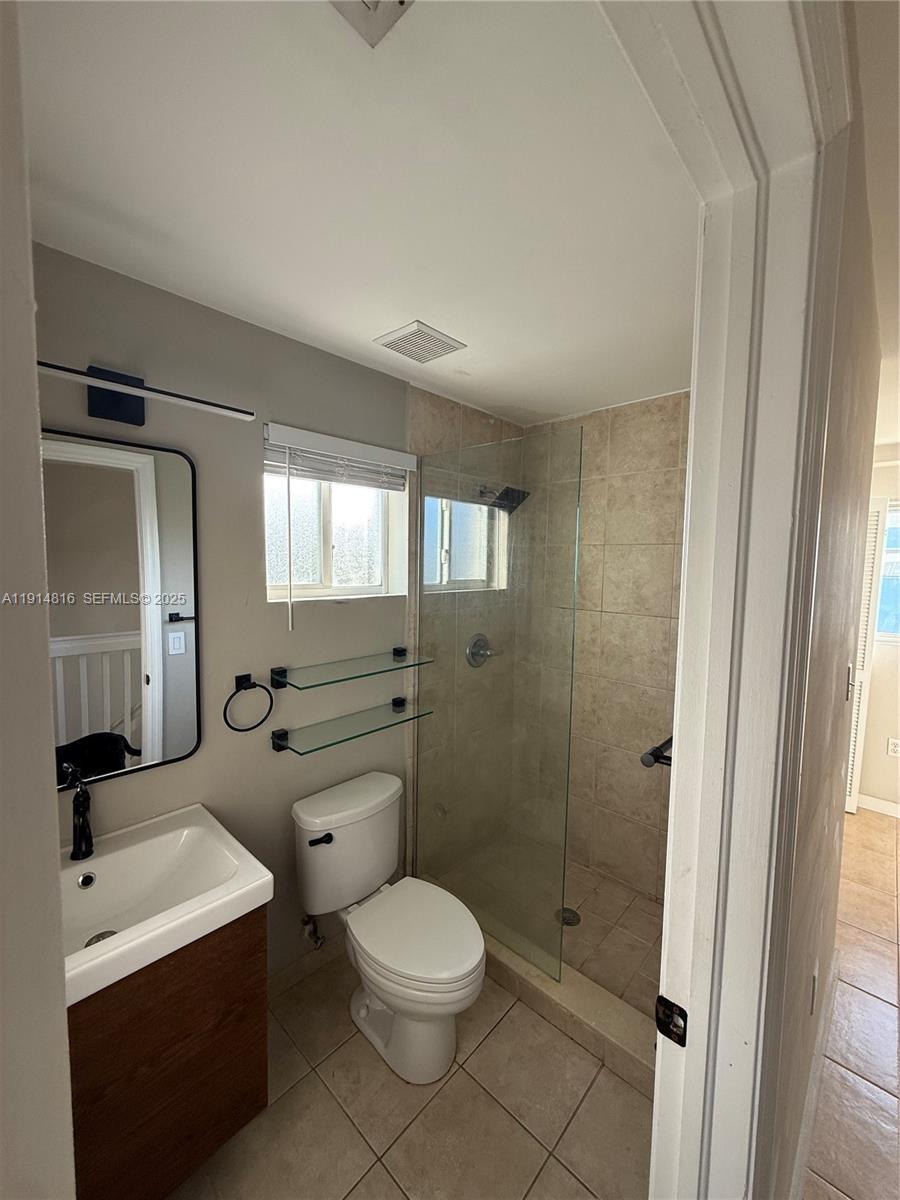 821 Southwest 2nd Street, Unit 1 Miami, FL 33130 - Photo 12 of 28 a bathroom with a toilet a sink a mirror a window and vanity