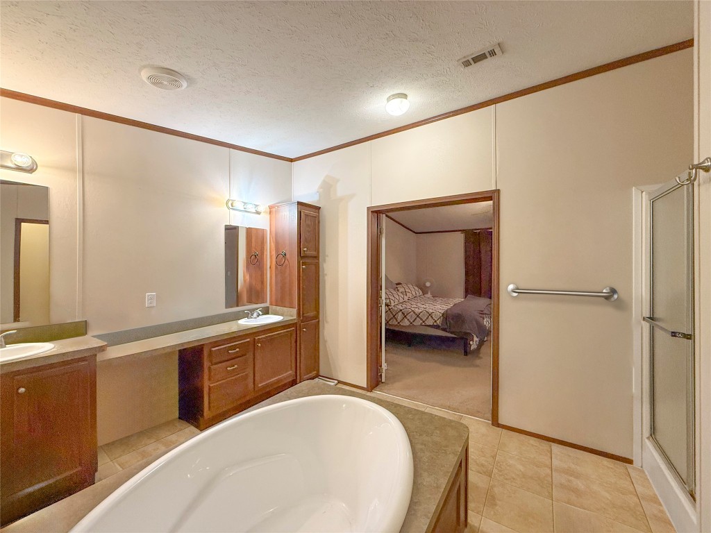 845 Caldwell Street Lexington, TX 78947 - Photo 9 of 39 Full bathroom featuring crown molding, double vanity, a bath, connected bathroom, and a walk-in shower