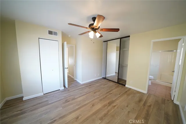 an empty room with wooden floor and a ceiling fan