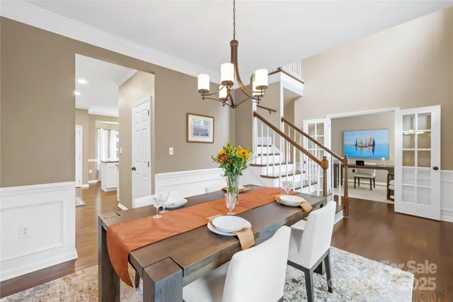 a dining room with wooden floor a chandelier a wooden table and chairs