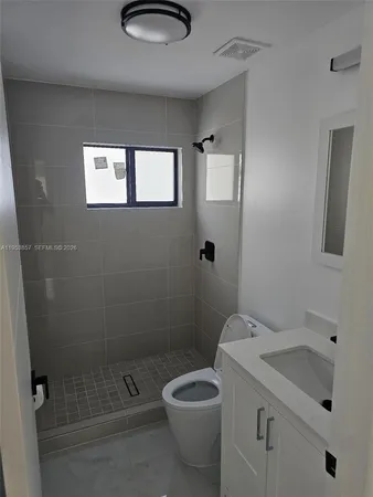 a bathroom with a granite countertop toilet a sink and shower