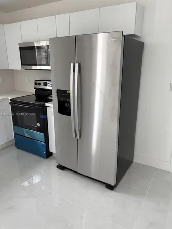 a kitchen with stainless steel appliances a refrigerator a microwave a sink and cabinets