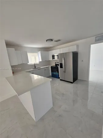 a view of a kitchen with refrigerator and white cabinets