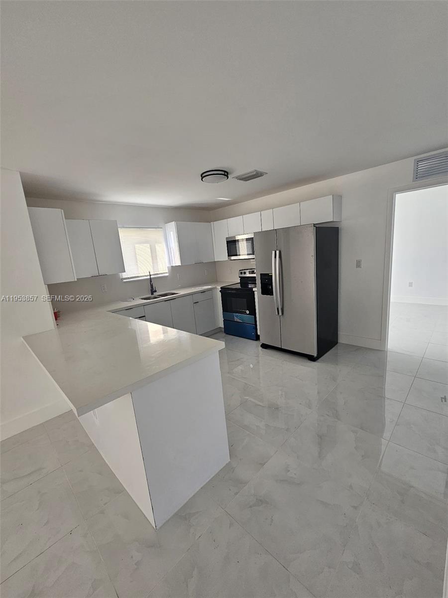 11997 Southwest 218th Street Miami, FL 33170 - Photo 6 of 16 a view of a kitchen with refrigerator and white cabinets
