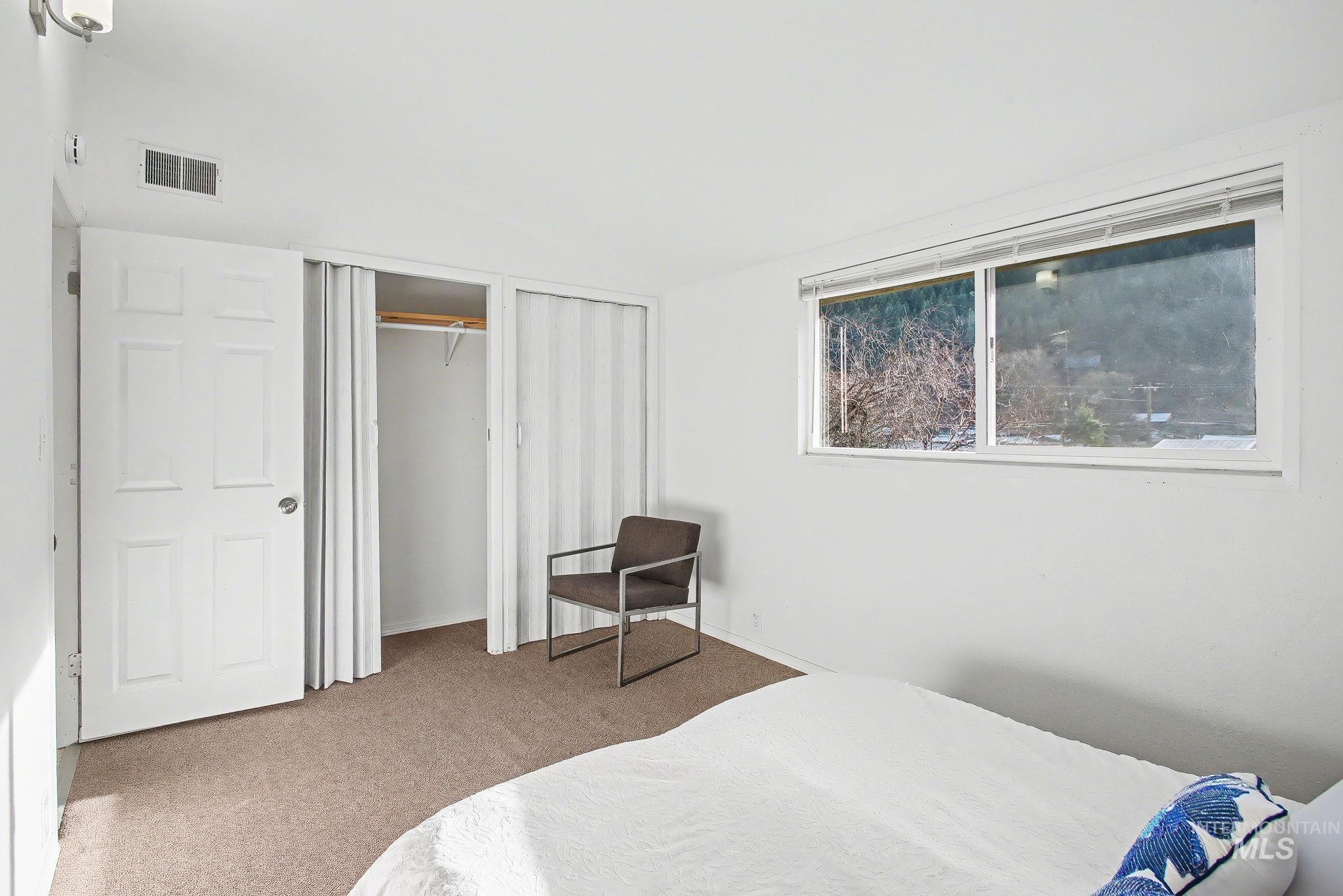 150 Elm Street Orofino, ID 83544 - Photo 16 of 36 Bright room featuring a large window, carpet flooring, a white six-panel door, and a built-in closet with accordion-style doors and a clothing rod