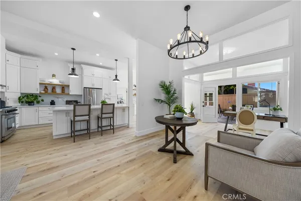 a living room with lots of furniture kitchen view and a chandelier