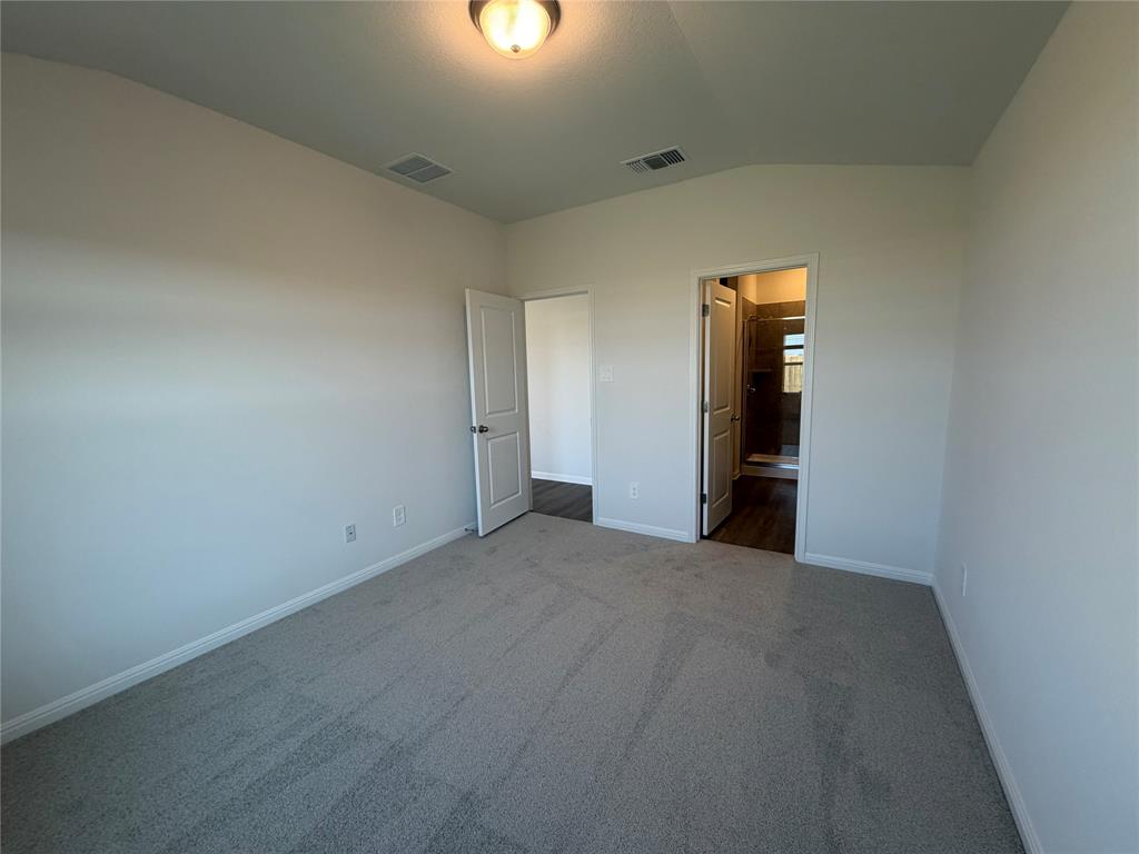 121 Honey Bee Road Jarrell, TX 76537 - Photo 5 of 10 A spacious bedroom offers a tranquil retreat with soft carpeting and easy access to a private bath.