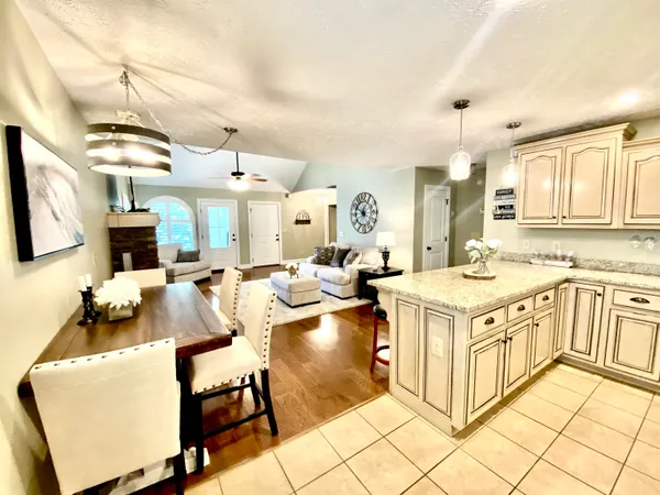 a kitchen with stainless steel appliances kitchen island a stove a sink dishwasher and white cabinets with wooden floor