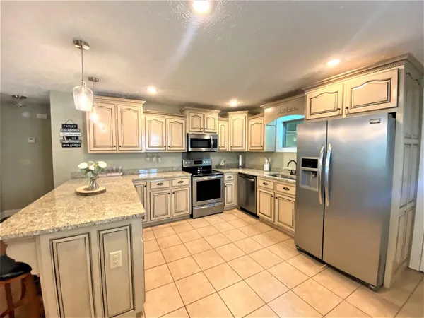 a kitchen with granite countertop a sink stainless steel appliances and white cabinets