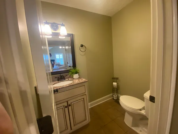 a bathroom with a granite countertop toilet sink and mirror