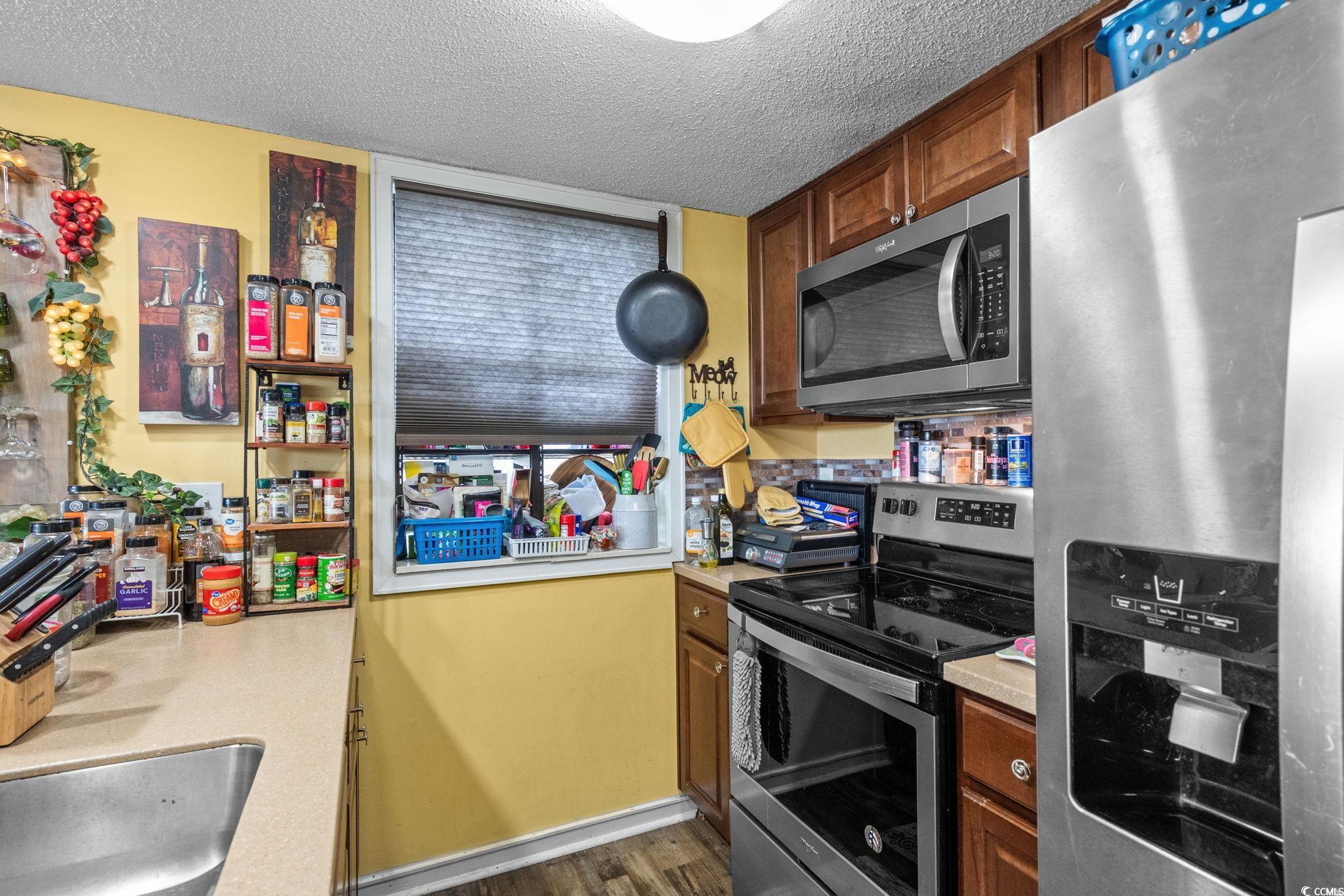 351 Lake Arrowhead Road, Unit 275 Myrtle Beach, SC 29572 - Photo 4 of 37 Kitchen featuring appliances with stainless steel finishes, light countertops, a textured ceiling, and brown cabinets