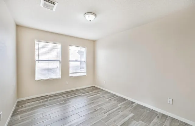 an empty room with wooden floor and windows