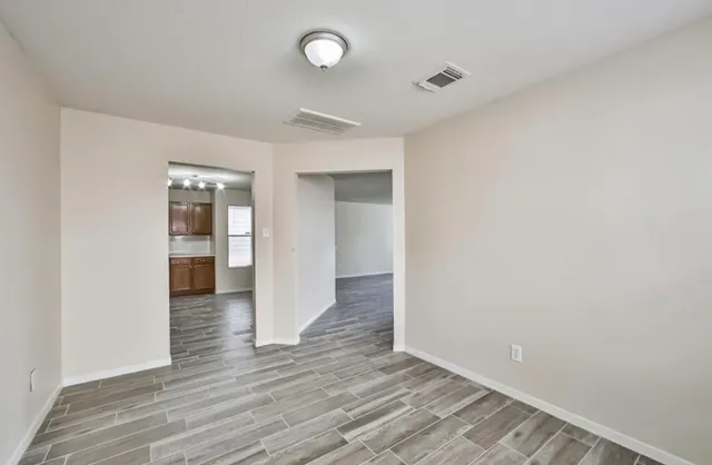 a view of an empty room with wooden floor and closet
