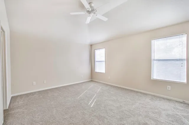 an empty room with a window and ceiling fan