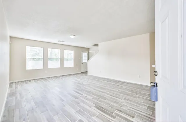 an empty room with wooden floor and windows