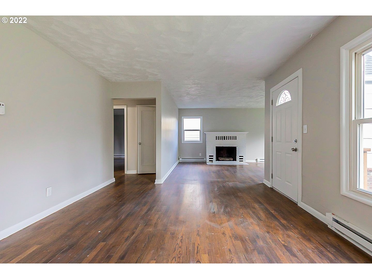 6930 Northeast Roselawn Street Portland, OR 97218 - Photo 2 of 31 a view of empty room with wooden floor and fireplace