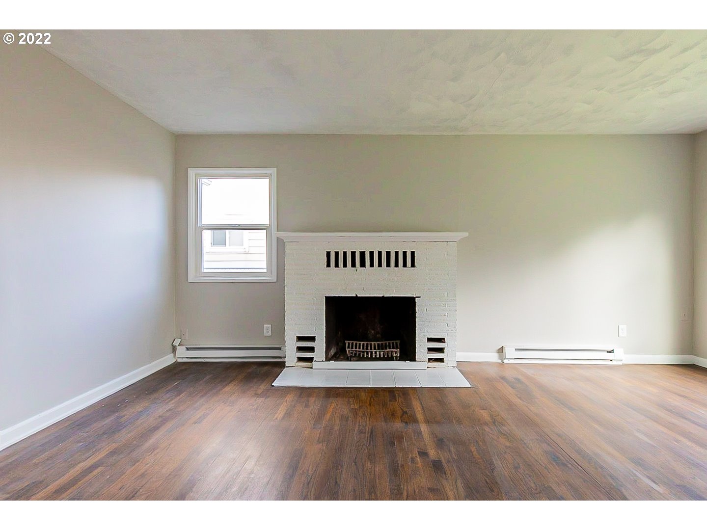 6930 Northeast Roselawn Street Portland, OR 97218 - Photo 4 of 31 a view of an empty room with wooden floor fireplace and a window