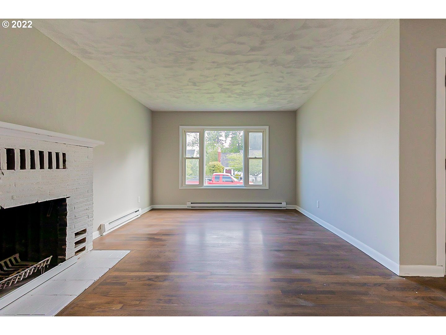 6930 Northeast Roselawn Street Portland, OR 97218 - Photo 5 of 31 a view of an empty room with wooden floor fireplace and a window