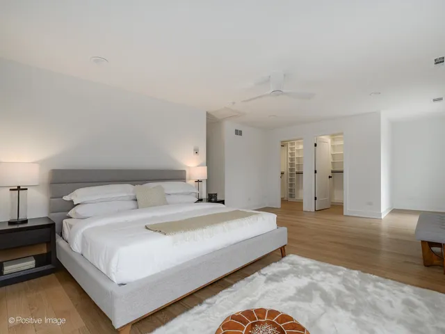 a spacious bedroom with a bed and a lamp